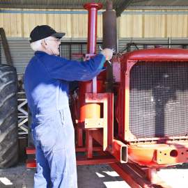 Tractor Museum of WA Whiteman Park volunteer working on red tractor